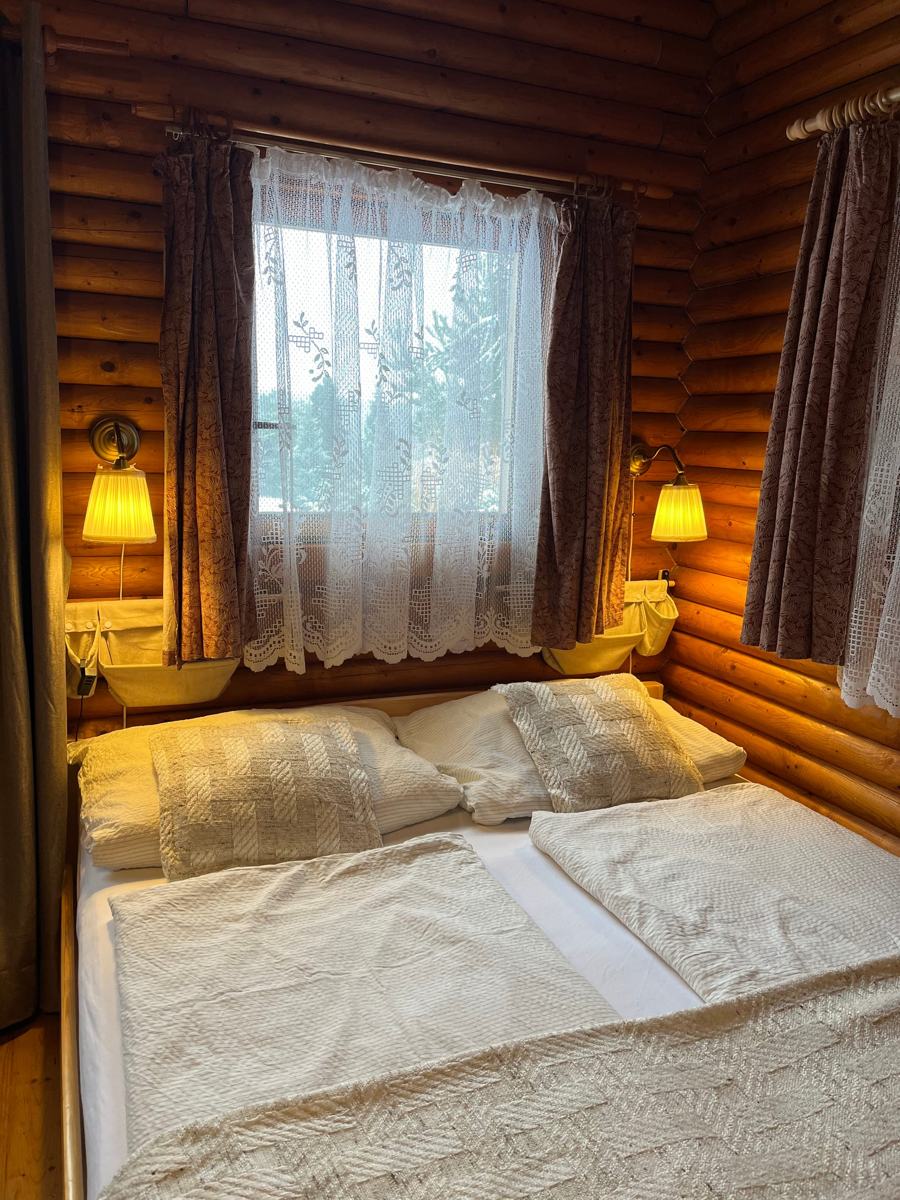 Manželská postel pod oknem s lampičkami ve večerním světle