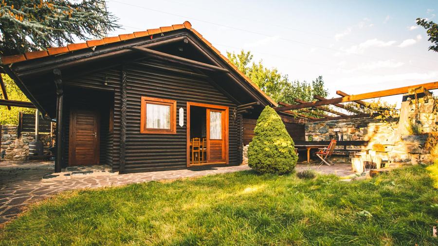 Tmavý srub s trávníkem a stromkem v létě